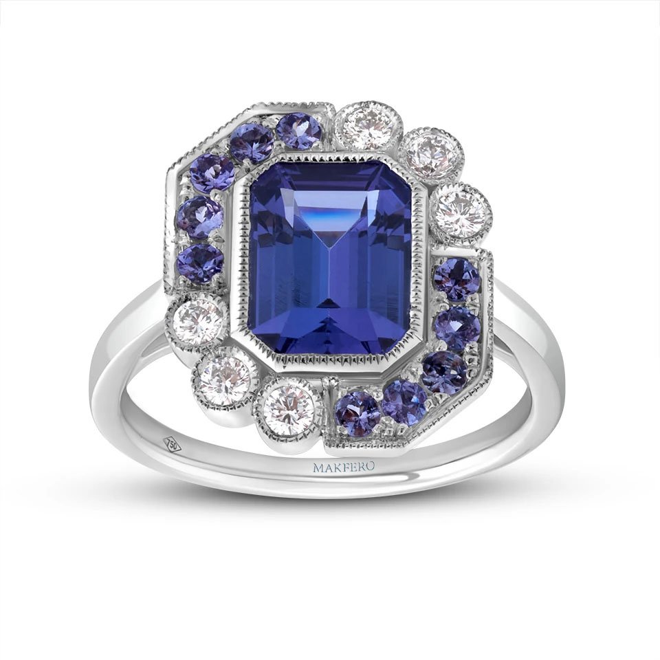 White gold ring with a central emerald-cut tanzanite, 7 × 9 mm, surrounded by six round diamonds and ten round tanzanites in a geometric halo design
