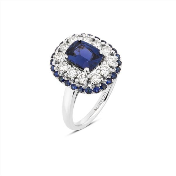 White gold ring with a cushion-cut sapphire, 6 × 8 mm, surrounded by 12 round diamonds and 26 small sapphires in a double halo